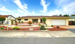 A real estate photo shows a nice yellow ranch home with front yard landscaping and a "for sale" sign in front.