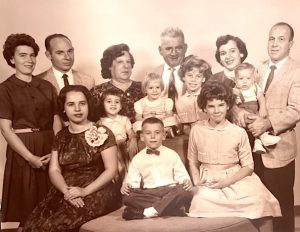 Aunts, uncles, grandparents, parents, siblings and cousins pose for this sepia-toned formal family portrait.
