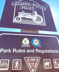 A close-up of signage for Martial Cotter Park in San Jose, on a wooden post against a blue sky.