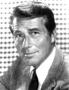 A vintage black-and-white publicity photo shows a close-up portrait of the actor Efrem Zimbalist Jr. in a suit jacket and tie.