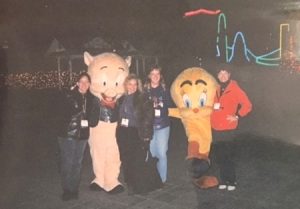 At night, several women pose with costumed characters dressed as Porky Pig and Tweety Bird. 