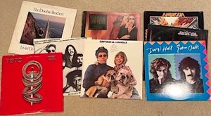 A selection of yacht rock vinyl albums is spread across a table surface. 