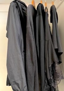 Black clothes hanging in a closet.