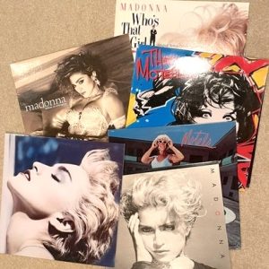 Vinyl album covers of Madonna and The Motels are spread across the top of a counter.
