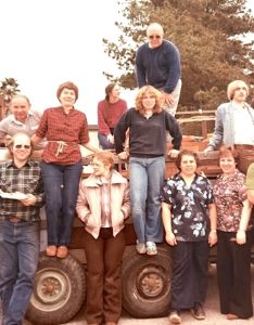 This snapshot, circa 1979-1980, shows a group of smiling family members standing in front of and on top of a vintage truck.