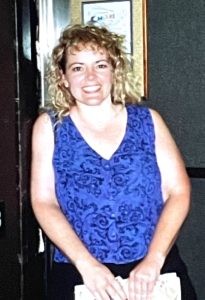 Peggy, on vacation, in a sleeveless violet-blue colored shirt.