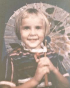 Studio portrait of a very young Peggy holding an umbrella.