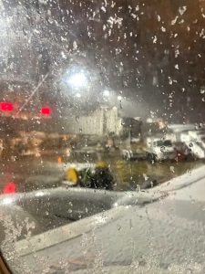 A snapshot of a wet and frosty airport tarmac, taken from inside an airplane window.